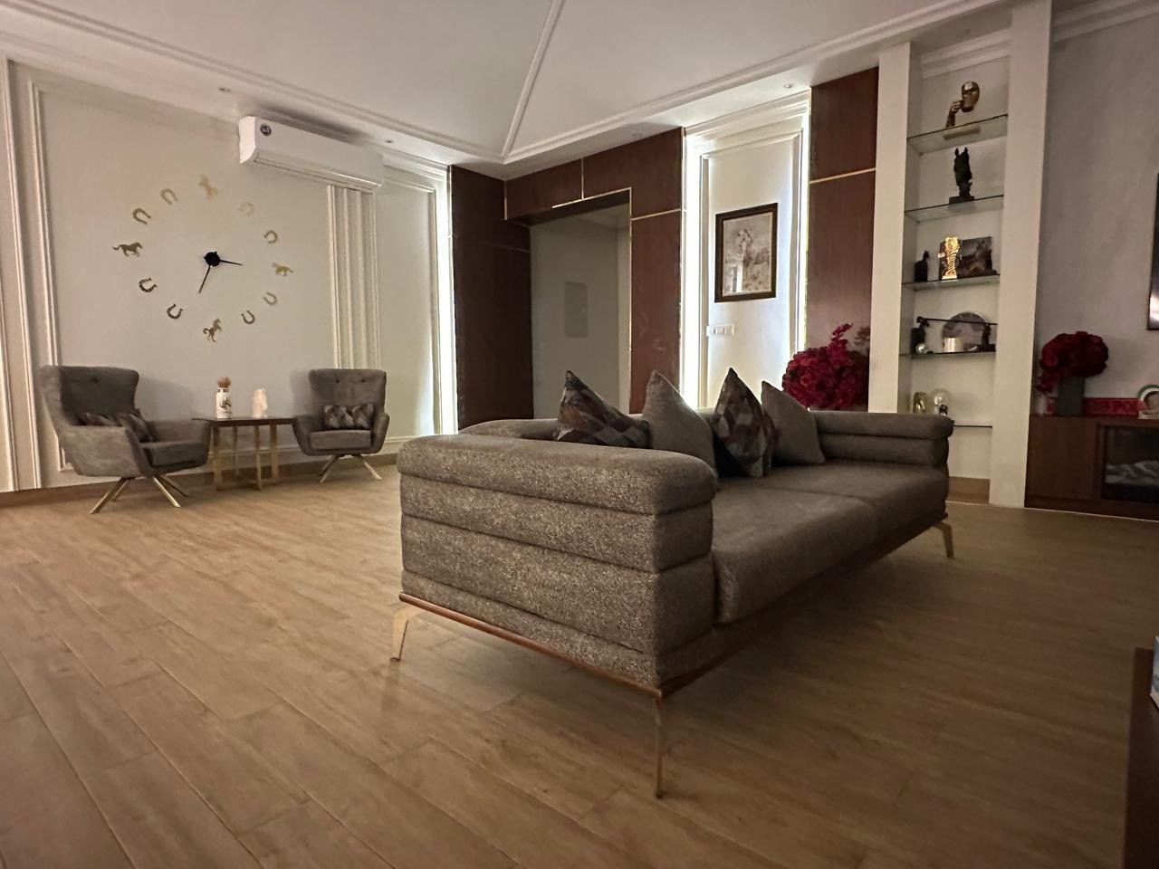 Sitting area with a textured sofa and armchairs on wide timber planks.