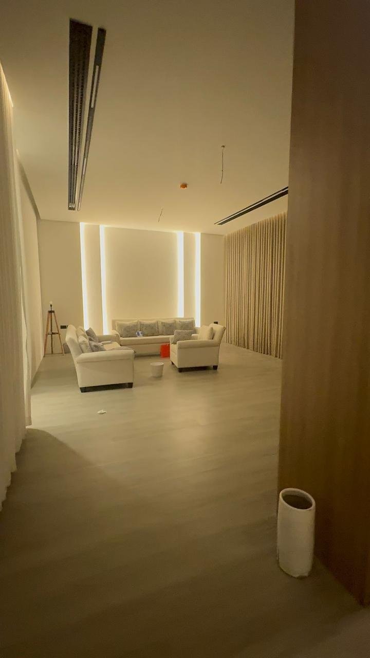 Warmly lit corridor opening into a lounge, framed by full-height timber panelling.
